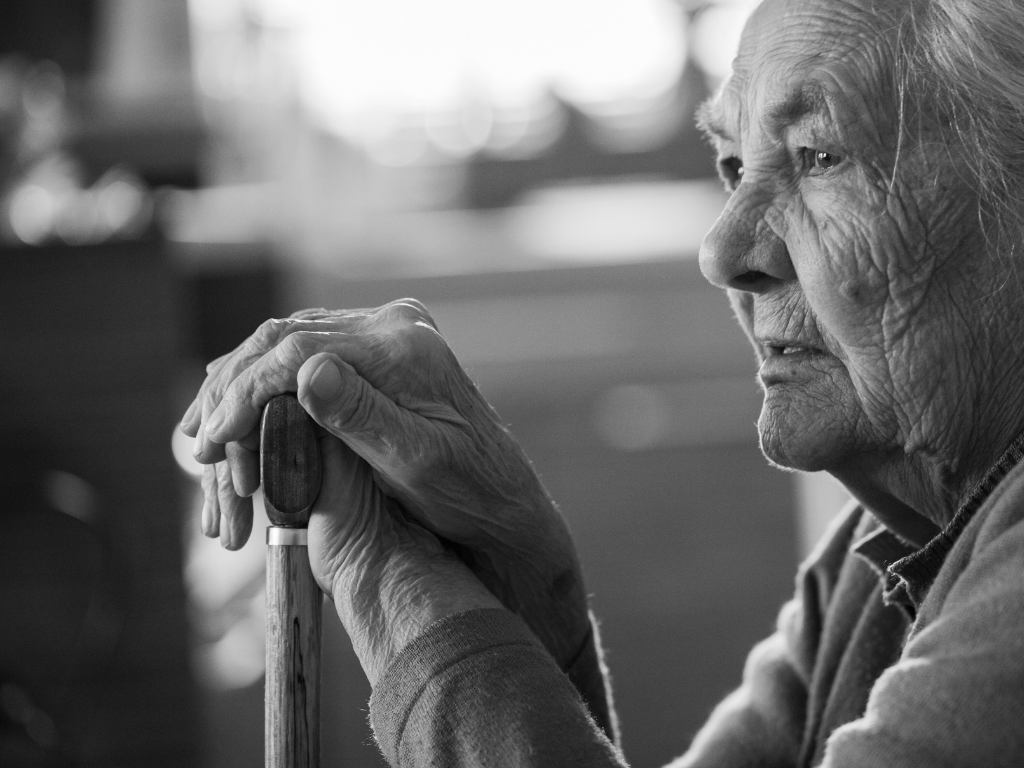 Older woman leaning on a cane.