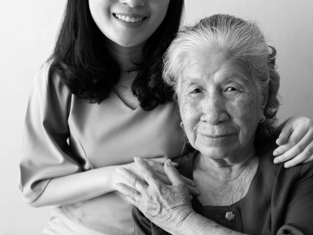 Older woman with younger woman's hand on her shoulder.