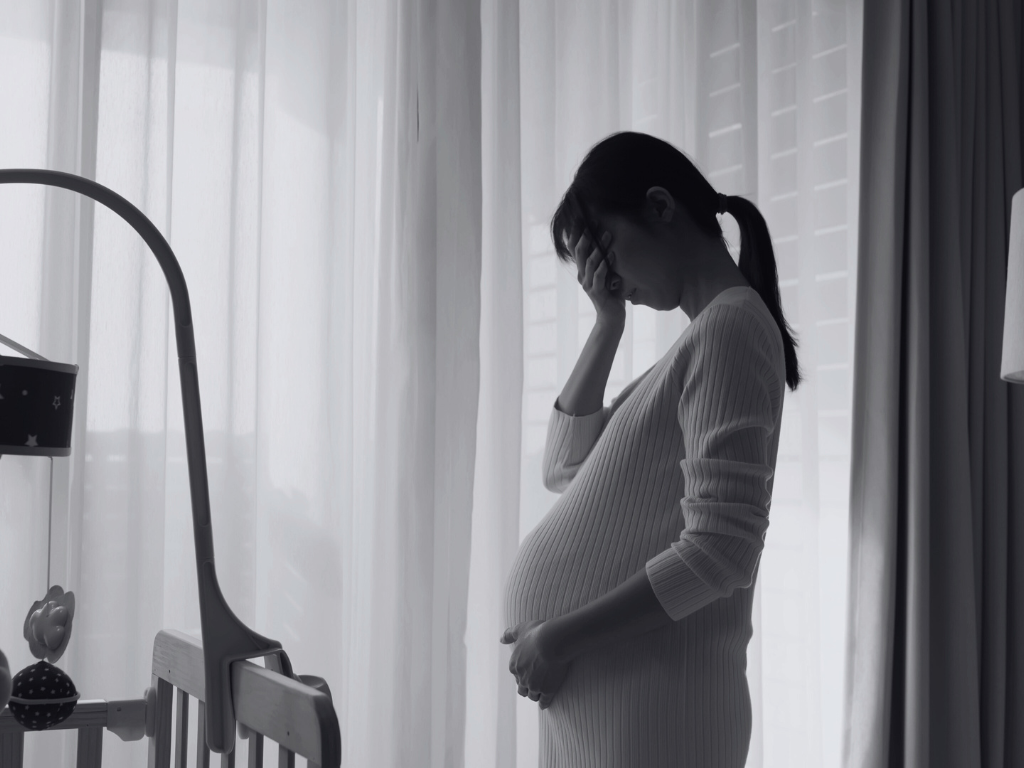 Pregnant woman with her face in her palm.