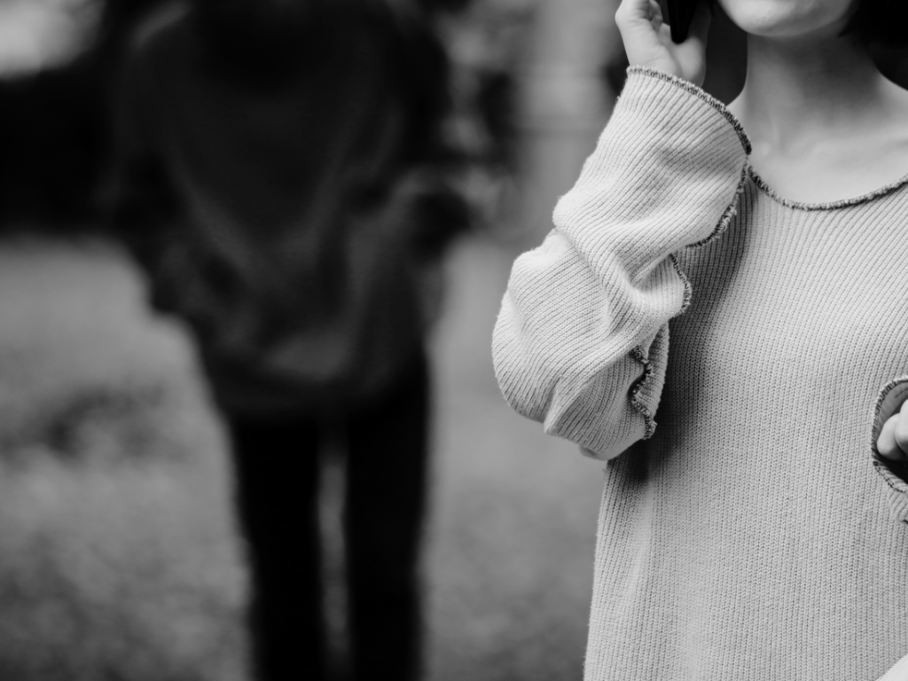 Man standing behind woman on the phone.