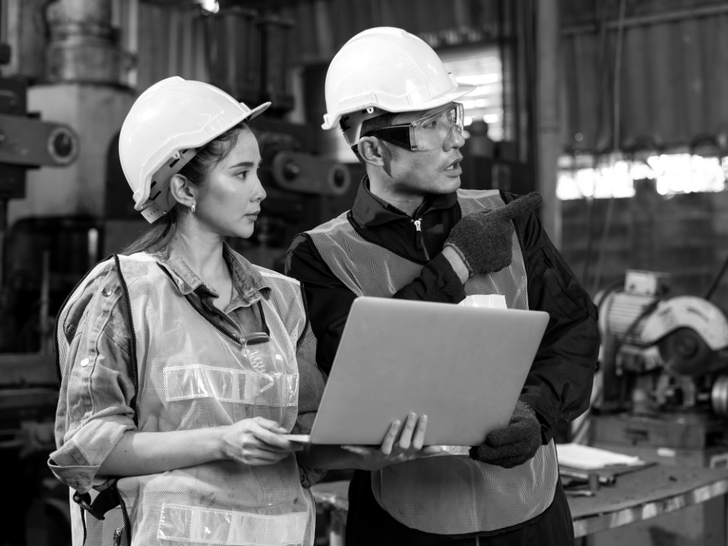 Woman and man wearing hardhats looking at laptop.